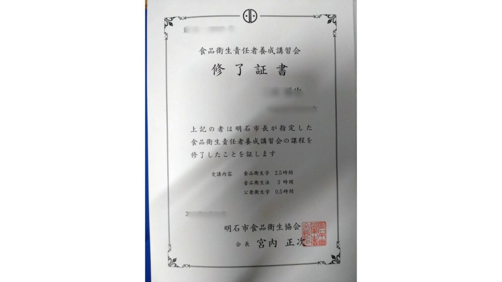明石市食品衛生協会が発行した食品衛生責任者養成講習会の修了証の実物。2022年2月21日に取得（第AS-XXXXX号）。