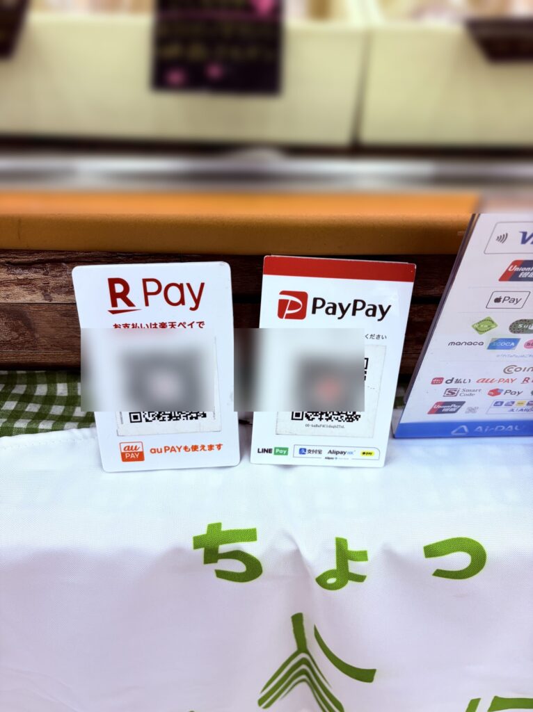 楽天ペイとPayPayのQR2枚を並べた『いろはのおと』店頭。楽天ペイ台紙下部に『au PAYも使えます』表示があり、共通QRでau PAYのお客さまも決済可能