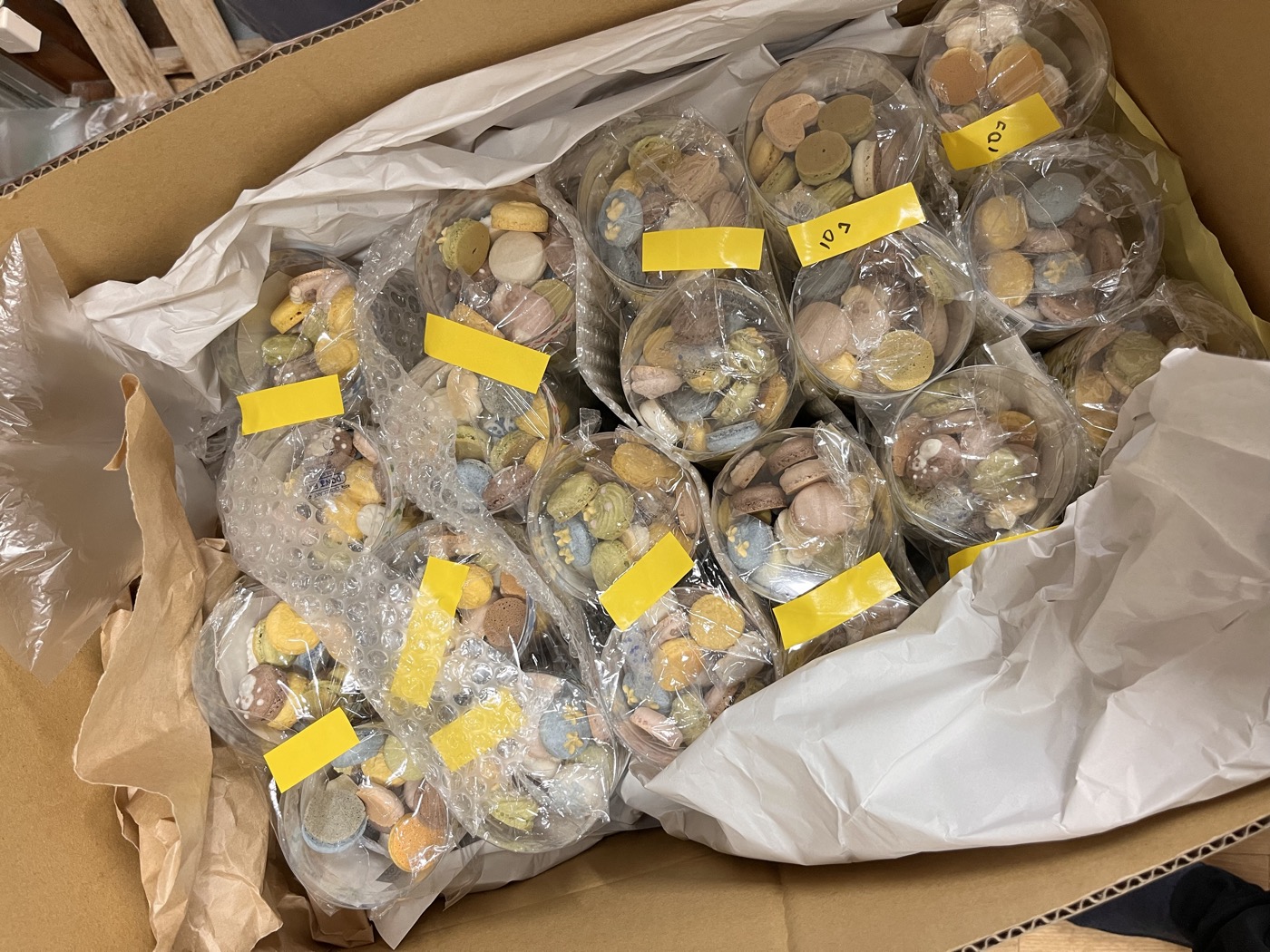 配送用のダンボール箱の内側に白い薄紙を敷き、個包装した商品をエアクッション袋で包んで詰めた状態。