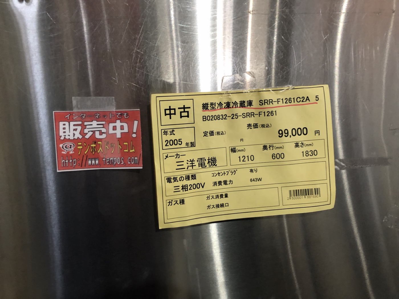 中古厨房機器店の縦型冷凍冷蔵庫に貼られた黄色い値札。三洋電機製SRR-F1261C2A、2005年製、三相200V、売価99,000円と印字されている。