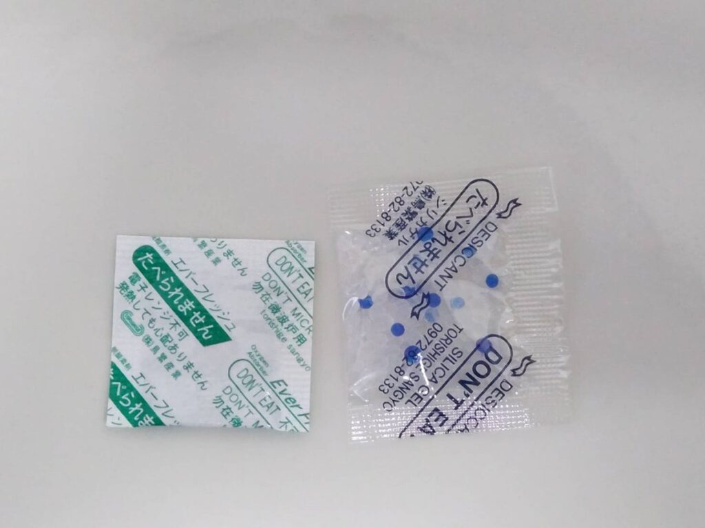 乾燥剤のシリカゲル（右）と脱酸素剤のエバーフレッシュ（左）。どちらも鳥繁産業の製品で、「たべられません」と書かれた小袋。