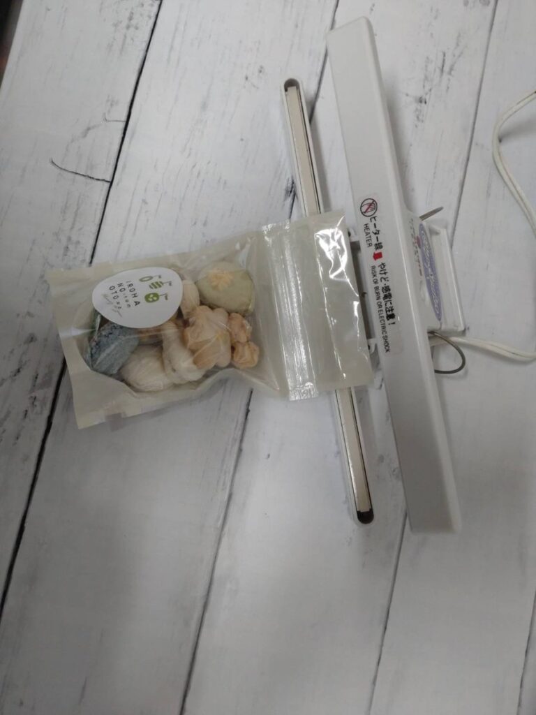 マカロンポーの袋のチャックの上を、クリップシーラーではさんでいるところ。