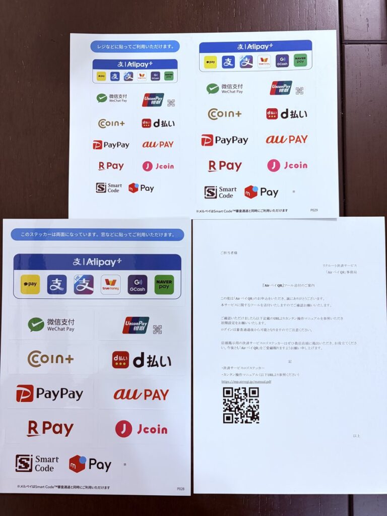 Airペイ QR事務局から届いた「ツール送付のご案内」と、お店に貼る決済サービスのロゴステッカー2種類（レジに貼るものと、窓に貼る両面のもの）。2026年10月